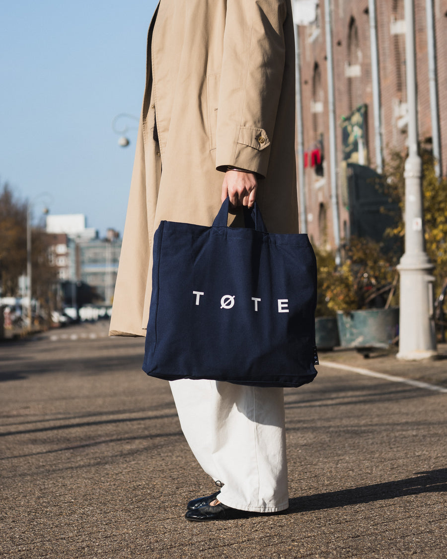 Navy Blue TØTE Bag carried by the handles on an Amsterdam street